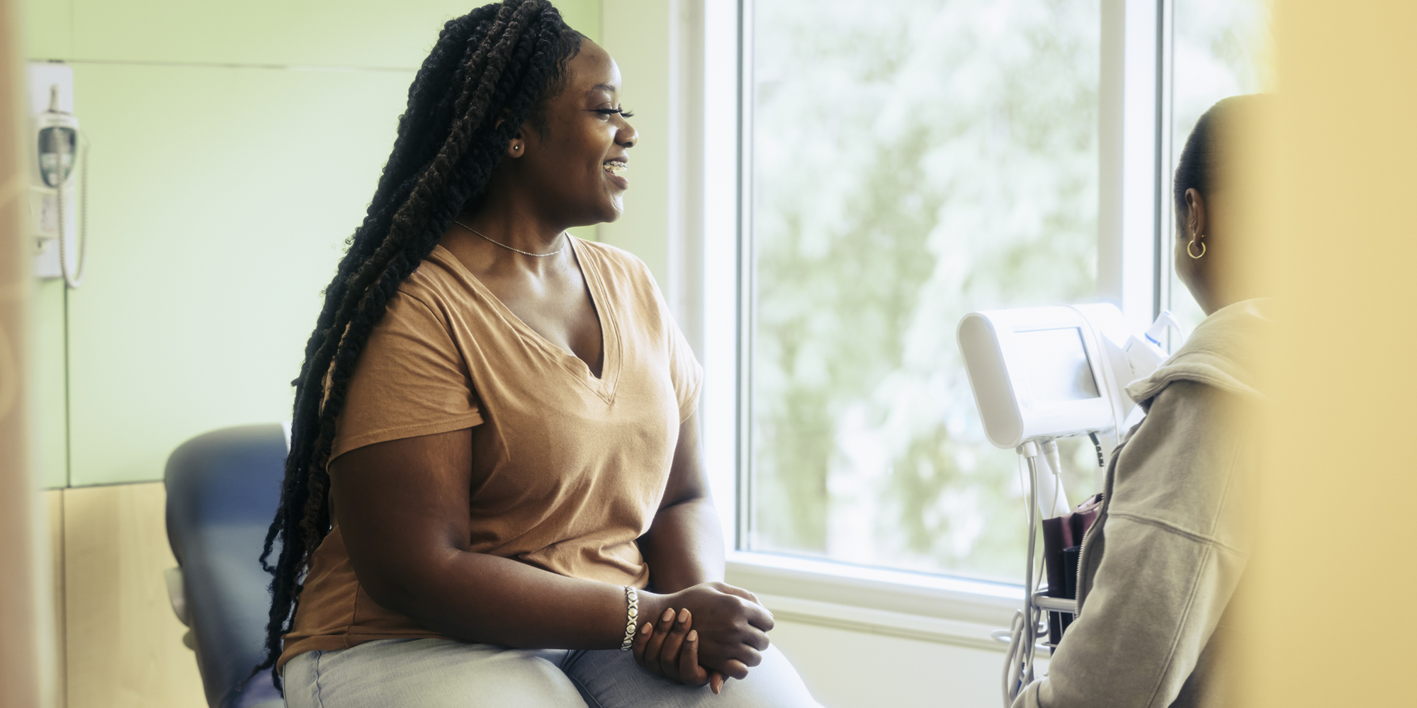 Smiling woman in the doctor’s office with doctor.