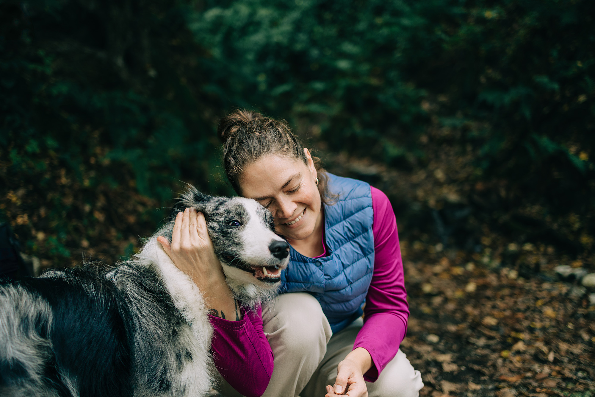 Woman outside with her arm wrapped around a dog