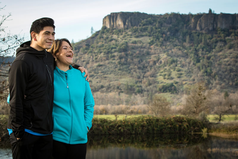 Madre e hijo parados, rodéandose con los brazos y sonriendo