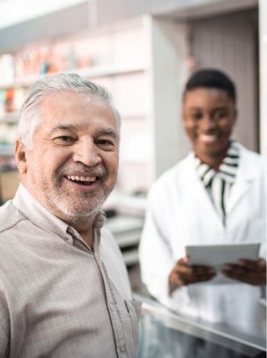 A senior man smiling as he talks to a pharmacist.